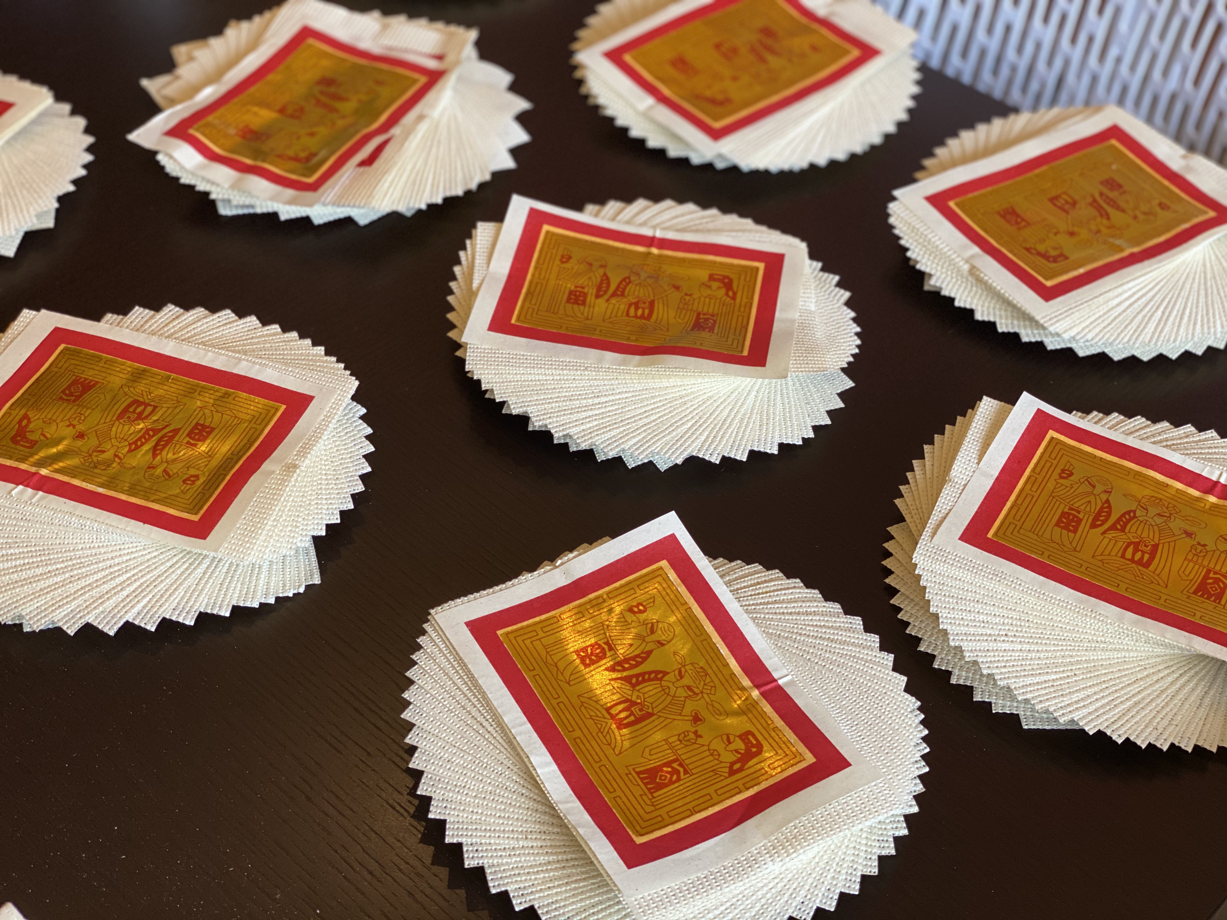 Joss paper sheets, rectangular with red ink and gold leaf, is arranged in stacks. The leaves of each stack are rotated to form a spiral.
