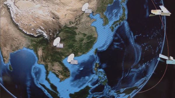 An image from a film, depicting one large part of Asia seen from orbital view, with icons pointing to satellite ground station sites.