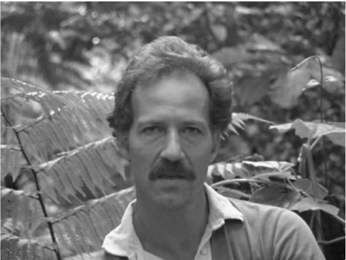 The exhibit displays a portrait of Werner Herzog with leaves in the foreground and trees further in the background.