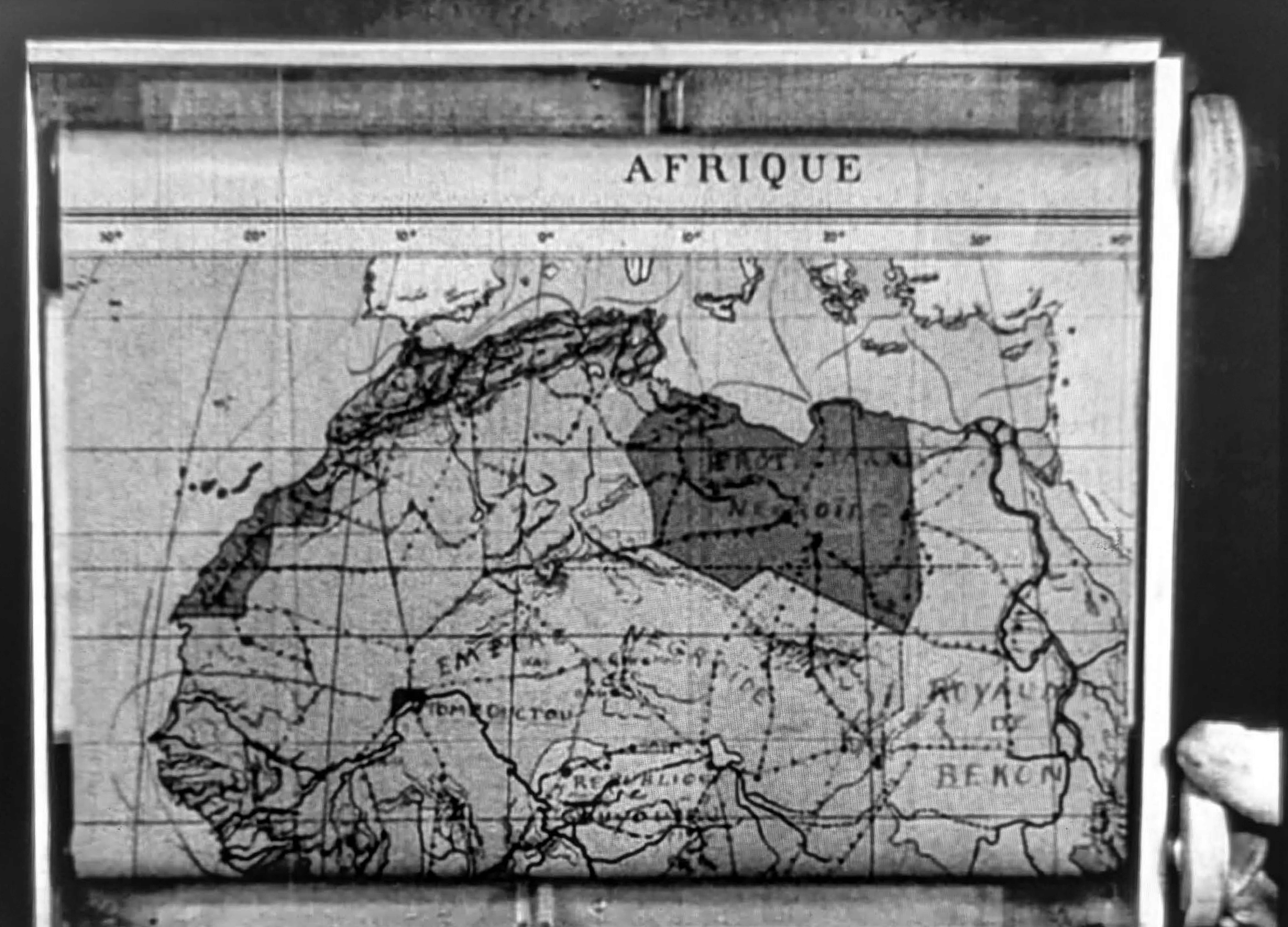 Still from Renoir’s film Charleston showing a scrolling map of North Africa and a gloved finger of the Black astronaut.