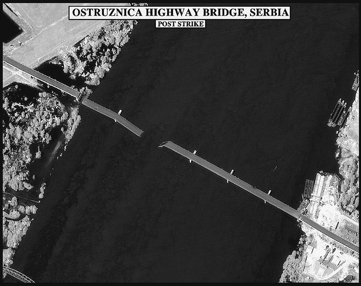 An infrared image showing an aerial view of a bridge that has been damaged by an airstrike, with one portion of the bridge collapsed into the water. The label reads “Ostruznica Highway Bridge, Serbia, Post Strike.”