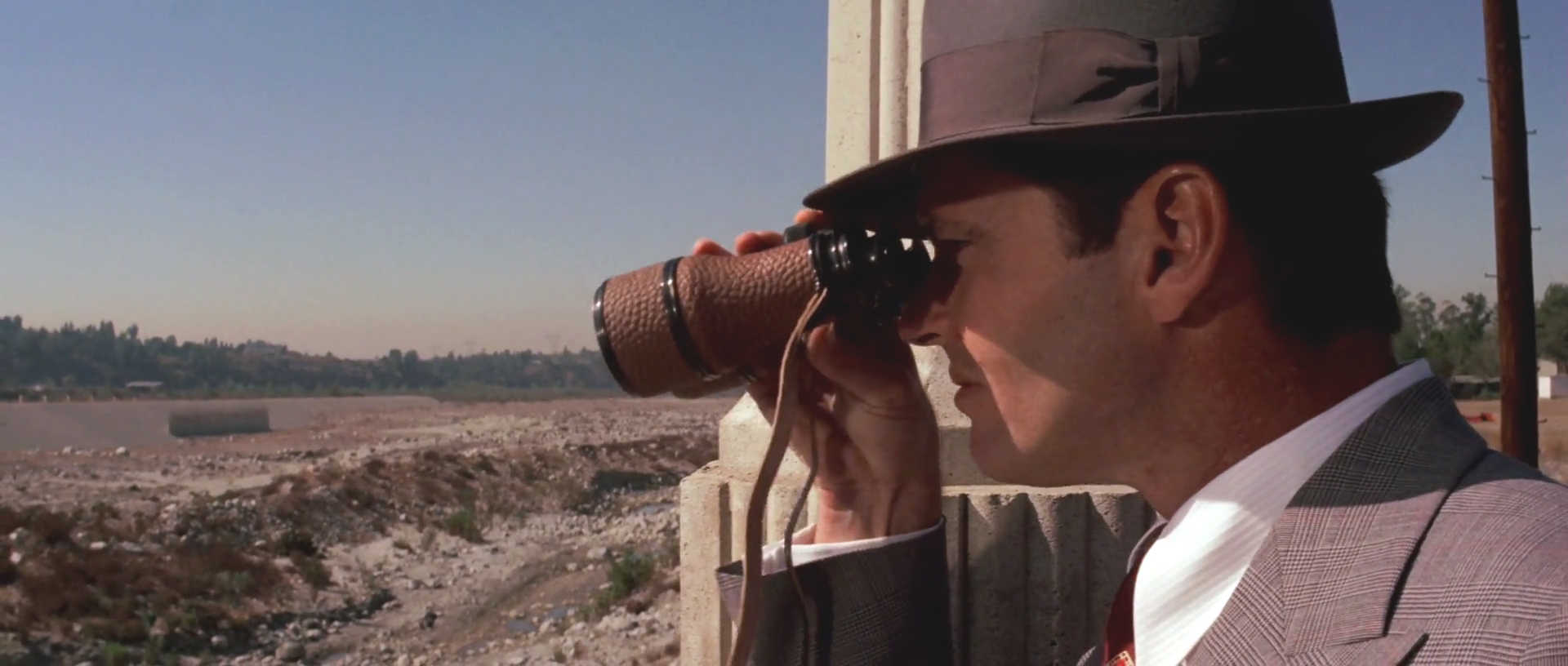 Jake looks through binoculars out across the dried-up bed of the LA River.