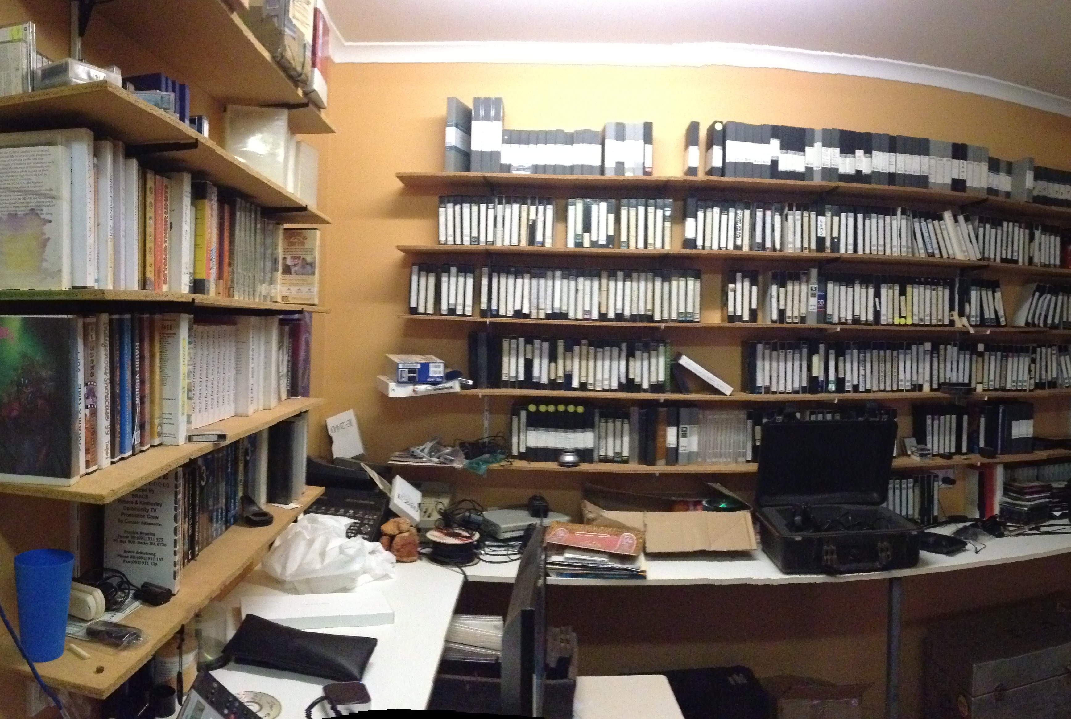 View of yellow-walled room with shelves on every wall, filled with archived media including DVDs and tapes.