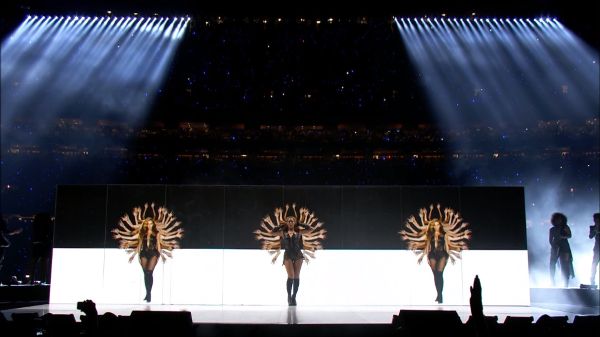 Distant shot of Beyoncé and two other dancers on stage.