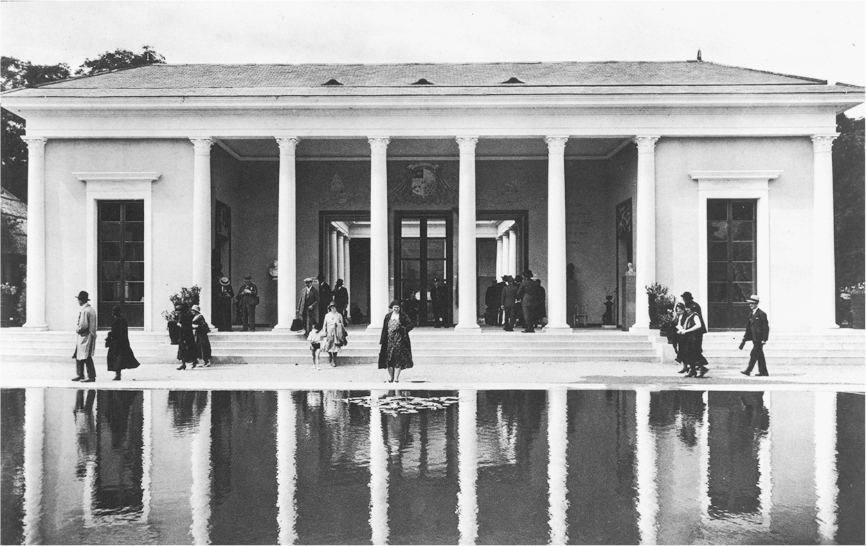 A photographof a facade of the reunion pavilion of the Colonial Exhibition with a pond.