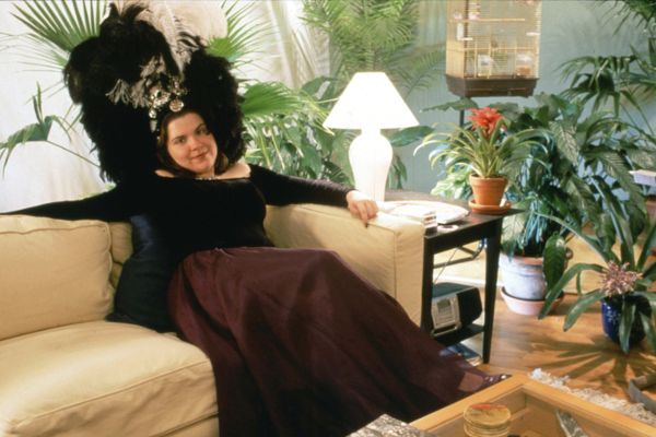 A woman sitting in the corner of a couch looking toward the camera.