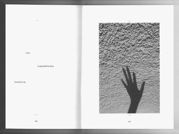 Open book spread showing a few lines of intentionally spaced words on the left and the shadow of a hand on the right.