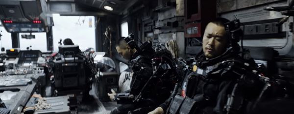 Interior of a craft with three individuals seated in spacesuits.