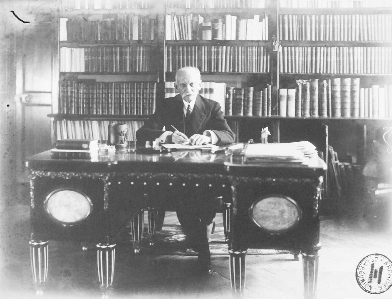 A photograph of Joseph Bédier sitting at a table while writing.