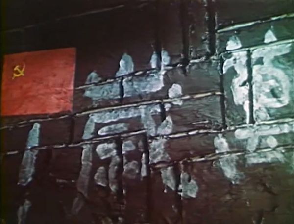 Painted graffiti on the wall with words in white and the image of a Soviet flag beside them.