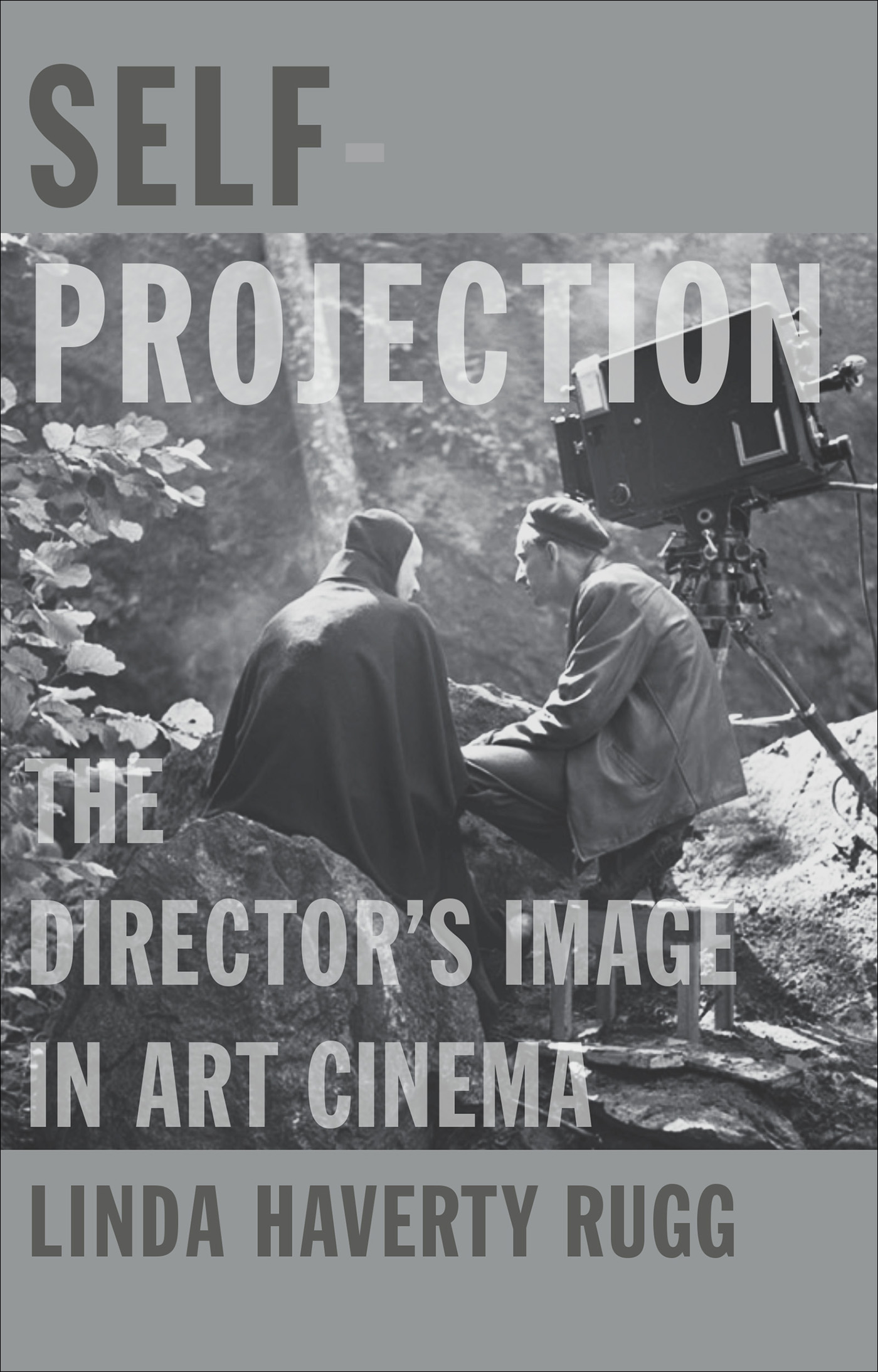 “The book cover of “Self Projection: The Director’s Image in Art Cinema” by Linda Haverty Rugg depicts two men seated on large rocks in a rugged setting in the woods, with a cinema camera visible just behind one of them.”
