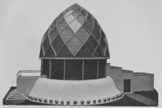 The exhibit features a scale model of Bruno Taut’s Glashaus, crafted by Emil Weinert. The model highlights a dome-shaped roof and a sturdy body reinforced with steel.