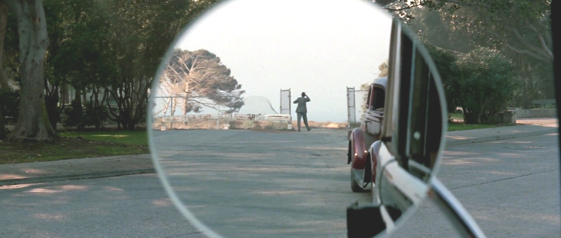 Tight shot of Jake’s rearview mirror which shows Mulwray walking away into the distance.