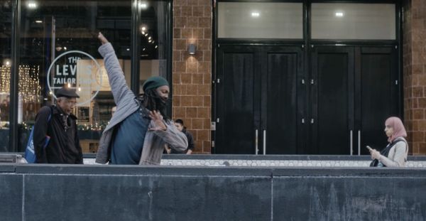Sideview of a person walking down stairs with their hands angled up and away from their body.