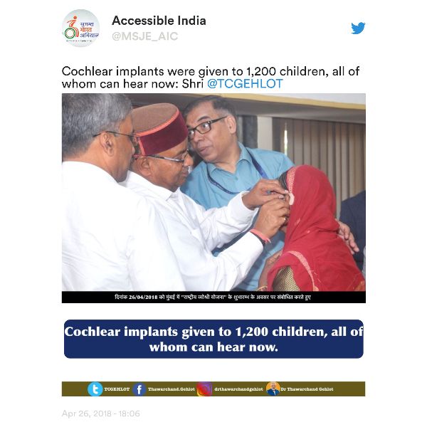 A tweet of a photo of three Indian men standing around a seated girl who faces away from the camera. A man places a hearing aid behind the girl’s ear.