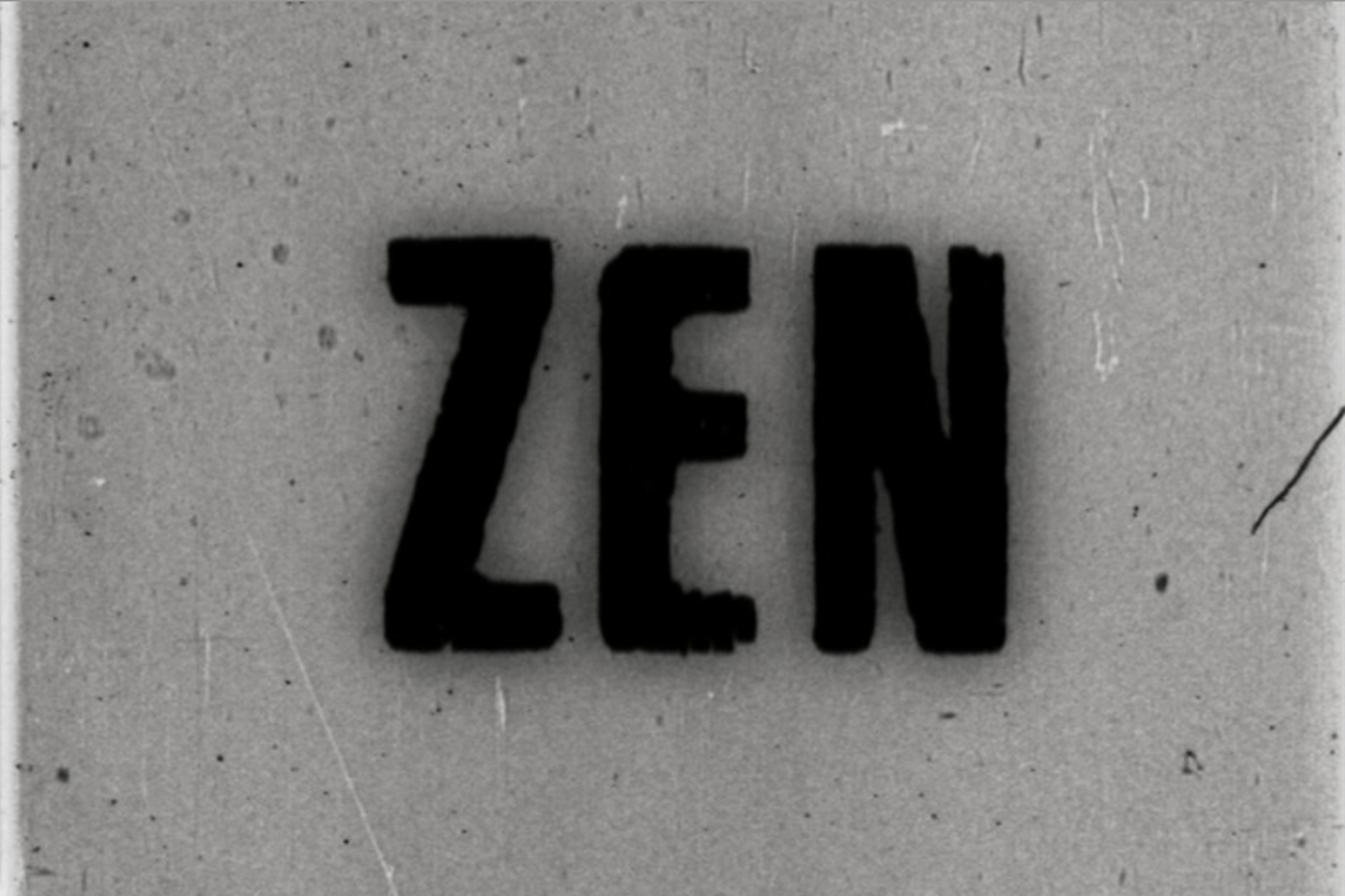 The word “ZEN” in large, bold, black letters on a gray, grainy background with many dust particles and scratches captured.