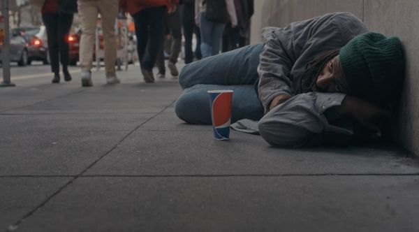 Person lying on a city sidewalk.