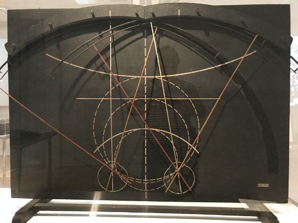 A model showing at bottom human eyes and, with differently colored materials arrayed in curves and straight lines, the range and focus of their vision.
