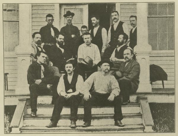 Fourteen men crowded onto three stairs and a porch landing.