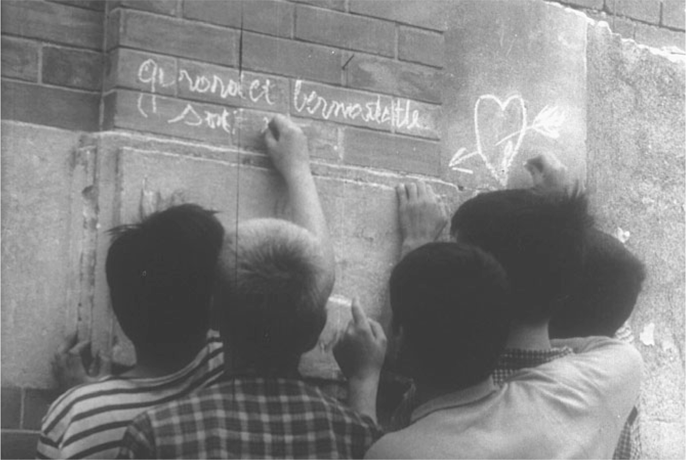 The exhibit presents a scene from the movie “Les Mistons” where the mischievous children are depicted starting a scene of writing on a wall.