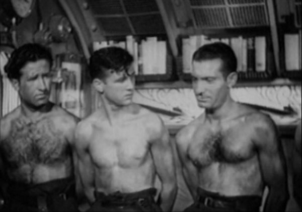 Three shirtless men stand side by side within a submarine chamber.