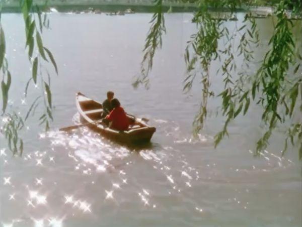 Scene of two people on a boat paddling from shore into a waterway on a sunny day.