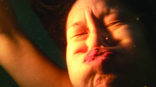 Face on shot of a person underwater with puckered lips.