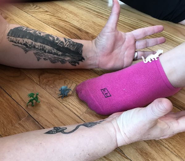 Two tattooed arms on either side of a pick-socked foot.