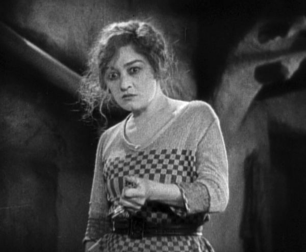 Woman with upset hair looking near camera with hand extended.