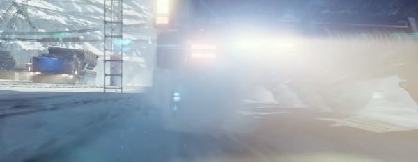 Ground-level shot of a vehicle travelling with its lights on in the snow.