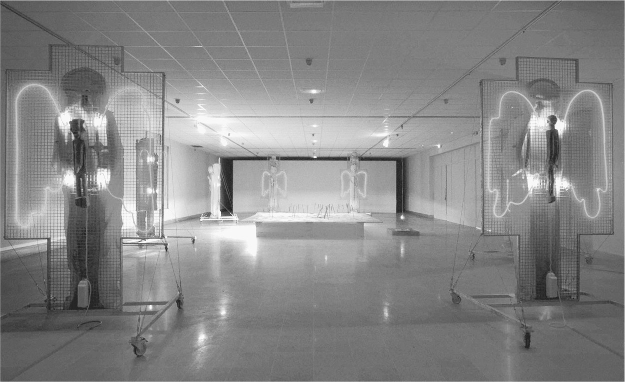 A photograph of a hall with statues with angel-wings. The wings are outlined with lights.