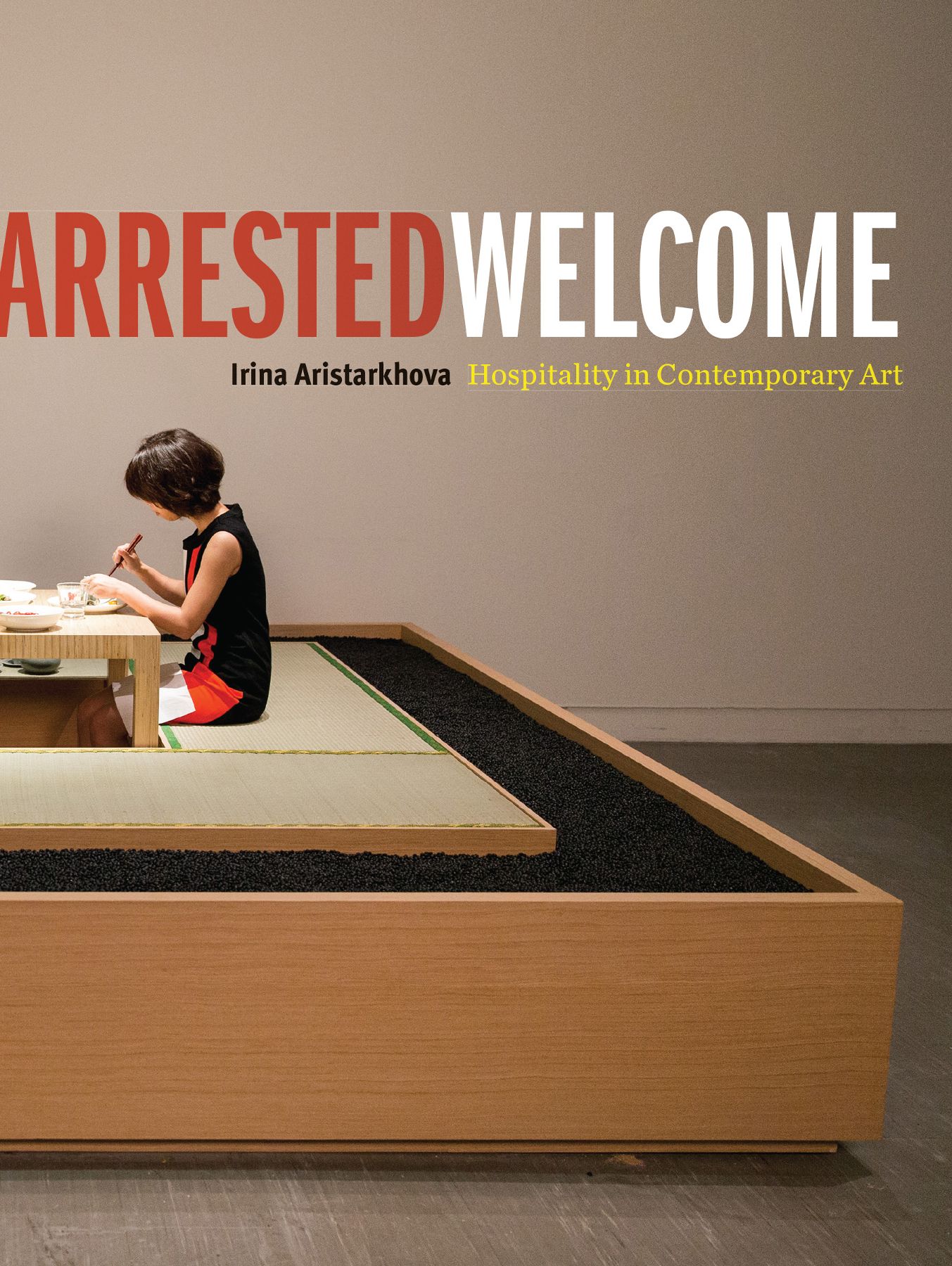 Book cover depicting the title in bold, capital letters, with the author and subtitle below. The background image is of an Asian woman sitting down to a meal at a table. The bench on which she sits surrounds the table, and is itself surrounded by a bed of small, black rocks housed in a wood container. The looks is one of very clean lines and evocative of a minimalist expression.