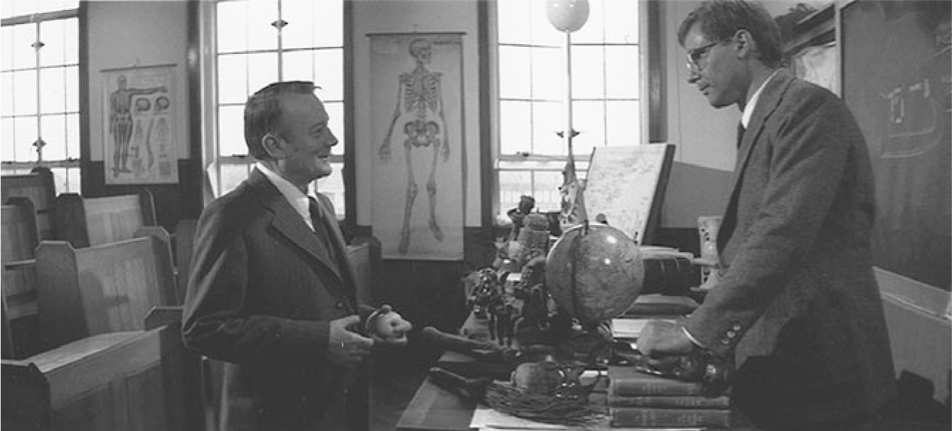 The exhibit displays a scene from “Indiana Jones and the Raiders of the Lost Ark” in a classroom, setting the stage for the map room. The scene includes educational elements such as a globe, an apple, wall maps, and scrolled maps, alongside Vesalian skeletons.