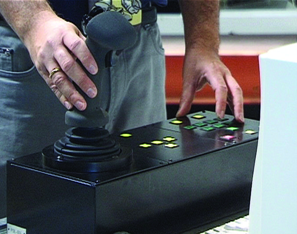 A male hand operating a control stick for remote operations.
