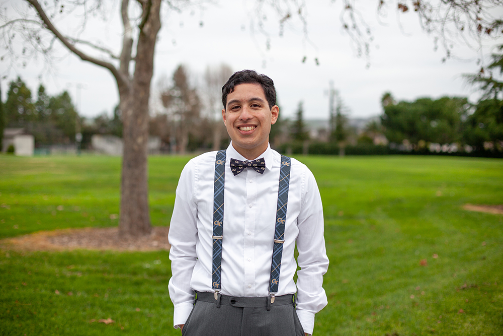 Antonio E. Contreras posing outdoors in front of a green space.