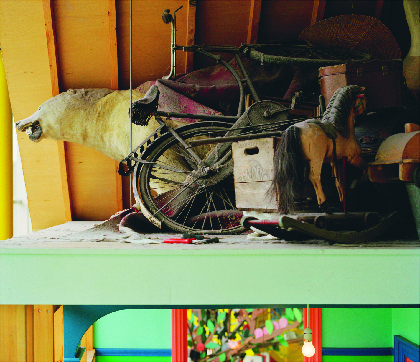 A cluttered attic space with various vintage items, including a bicycle, a rocking horse, and a taxidermy polar bear head.