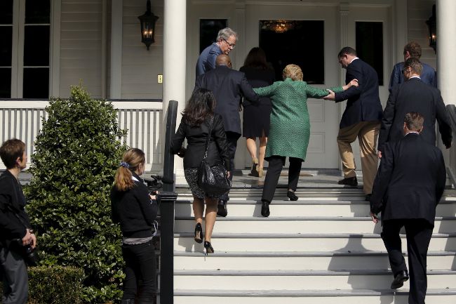Hillary Clinton on campaign trail in 2016 slips on steps and reaches out and is supported by her staff.