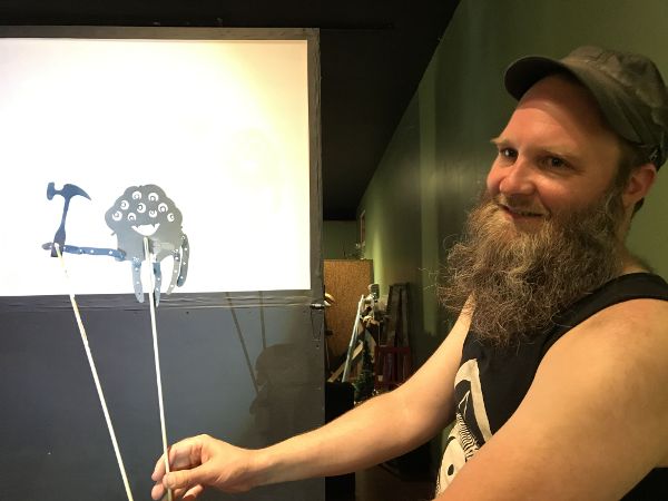 A view behind the shadow puppet screen showing the operator holding the puppet up.