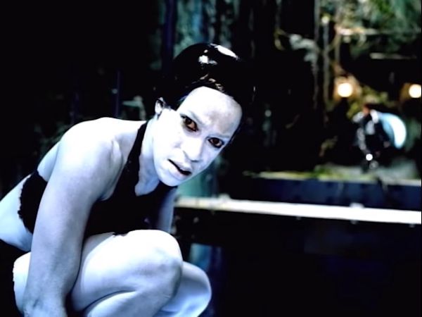 Dancer looking toward the camera with a leather helment and white body paint.