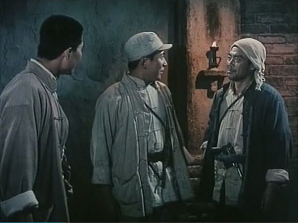 Three men standing side-by-side talking with one another.