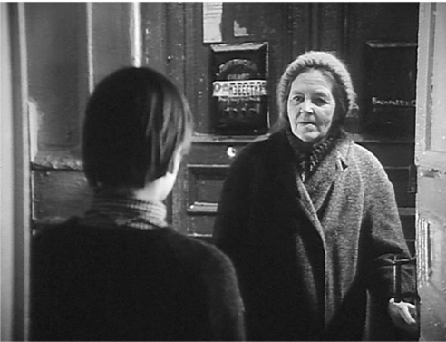 The exhibit features a still, a shoulder shot, from the movie “The Mirror,” depicting an elderly woman standing behind a door and an individual standing outside the door.