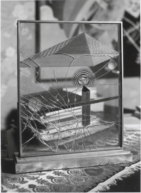 The exhibit showcases an artwork composed of cracked glass, which is framed and mounted on a wooden base.