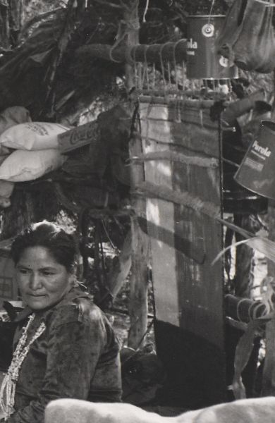 A loom hangs at the edge of a summer shelter, its warp and weft transformed by monochromatic photography into three oblongs of white, gray, and black.