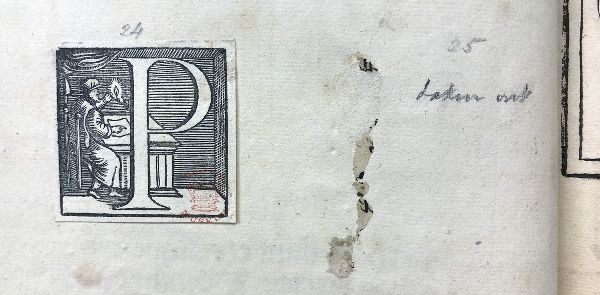 Detail of a page with a letterform of a block P; a capped figure sits behind it at a desk.