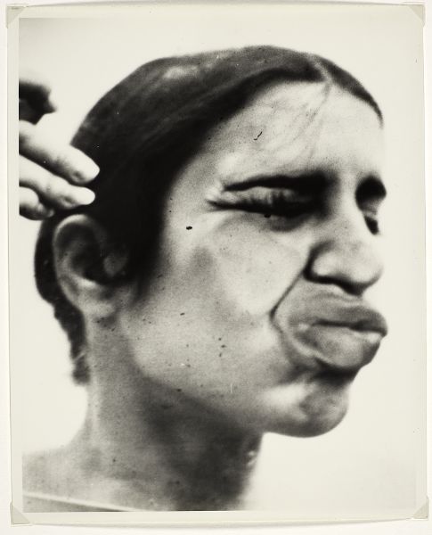Women pressing side of face into glass exagerating size of her mouth and compressing her right cheek and nose