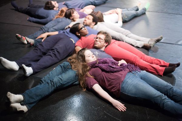 People laying onto of one another on a padded floor.