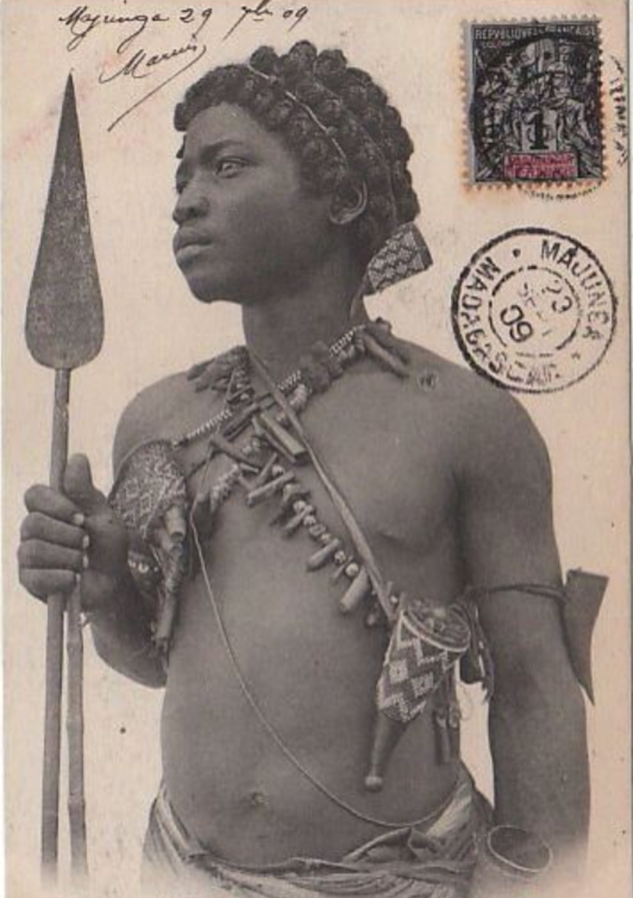 Postcard of the head and torso of an Indigenous Madagascar man with shell ornaments on his chest, holding a spear.