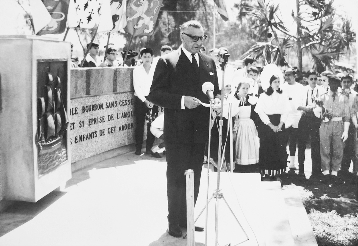 A photograph of Joseph Bedier delivering a speech while standing at a podium.