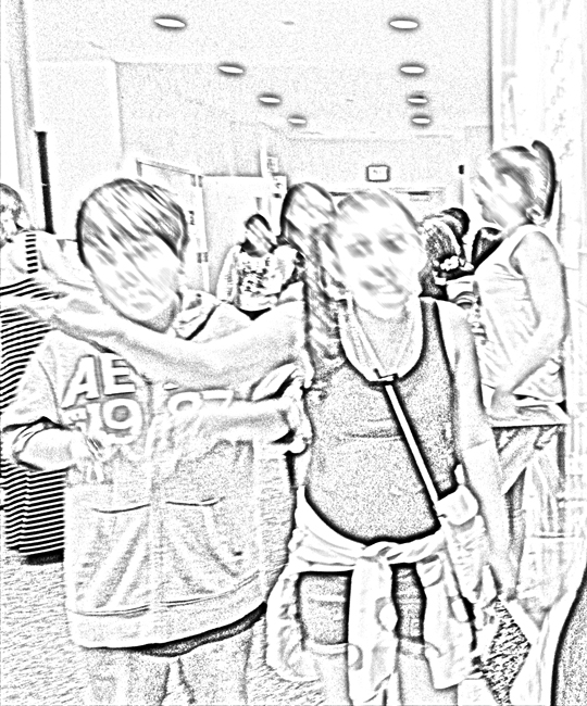 Aurora leads the way as her class walks down the hallway. Holding her notebook in one hand, she gestures upward with the other and talks with friends.