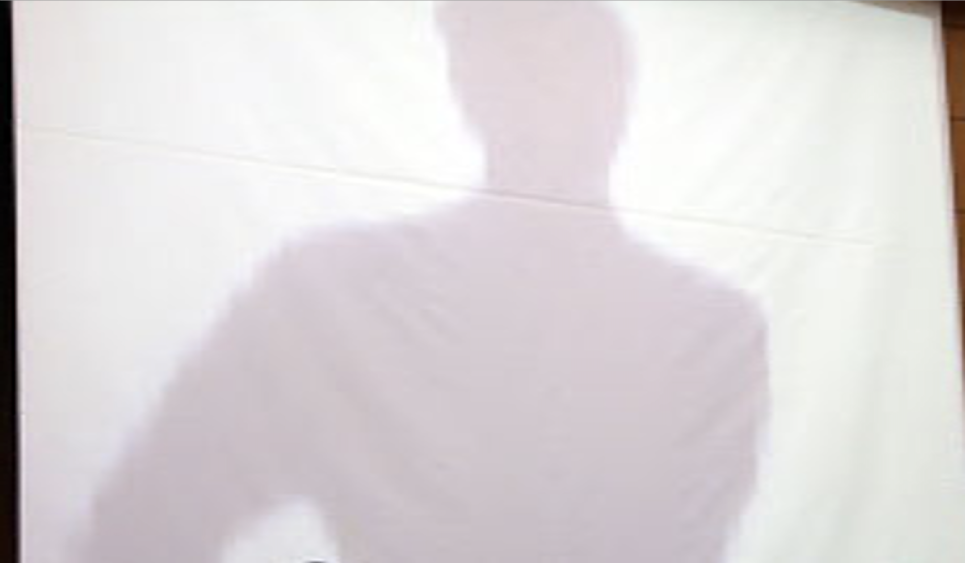 Shadow of a person projected on a crumpled white screen shot in low fidelity typical of early phone cameras.